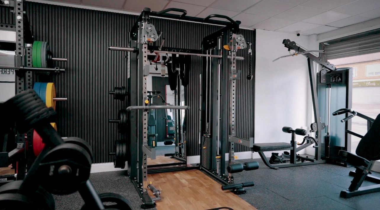 Half rack, Smith machine and cable station against a black slat wall